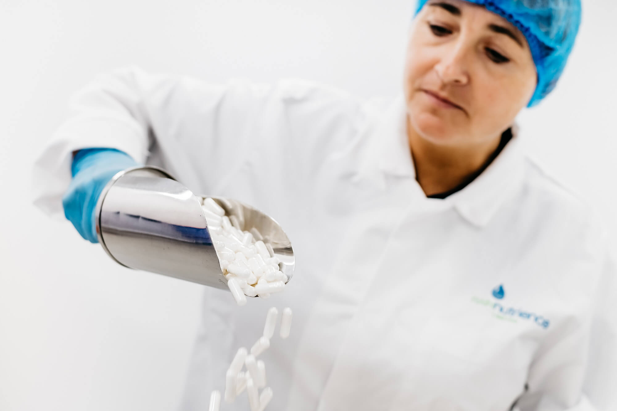 A woman in a lab coat pouring pills into a container.