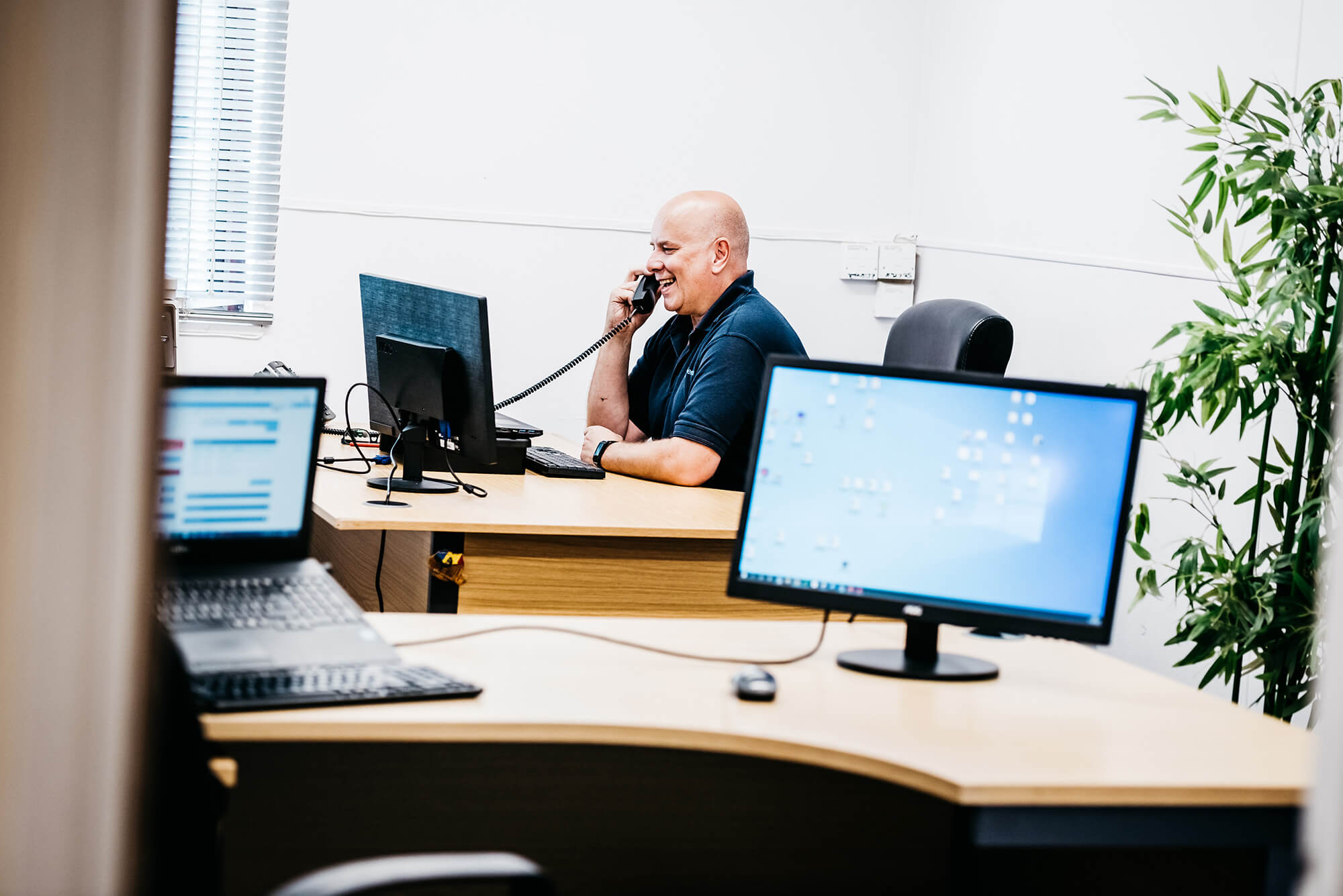 Man seated at a desk engaged in a phone conversation.