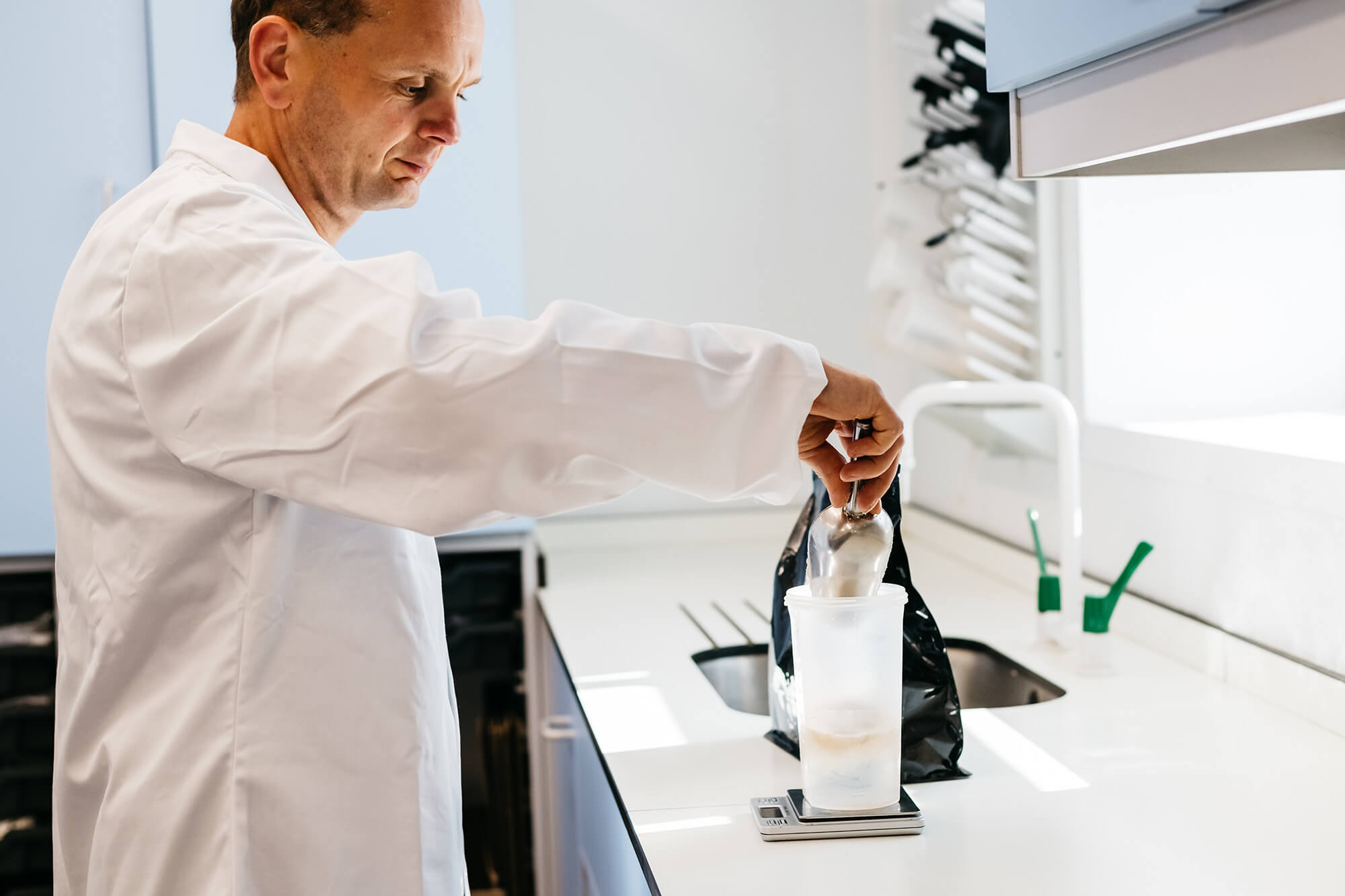 A man in a lab coat pouring milk into a glass.