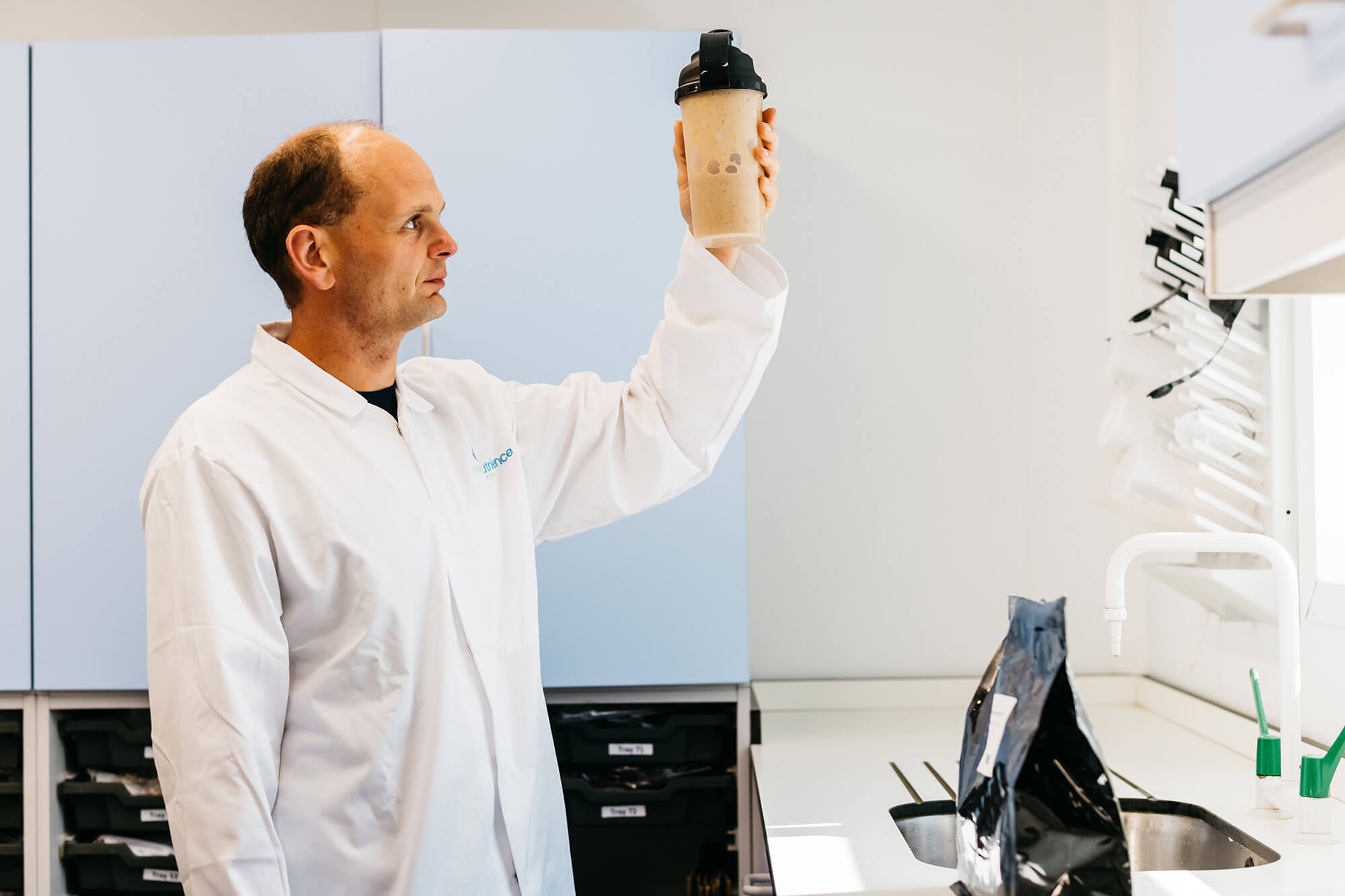 A man in a lab coat holding up a cup.